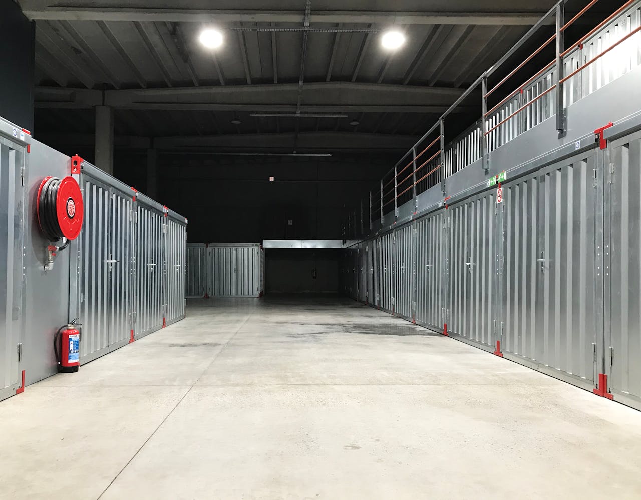 Spacious industrial warehouse interior featuring steel storage units and safety equipment.
